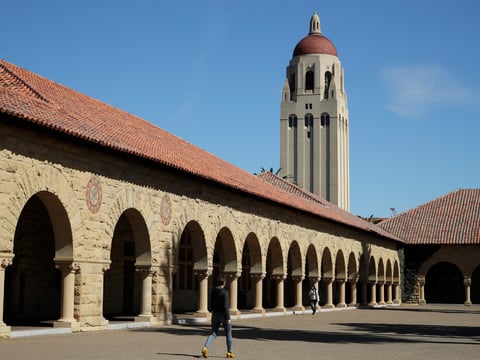 People walk on the Stanford University campus beneath Hoover Tower in Stanford, Calif., on March 14, 2019.
