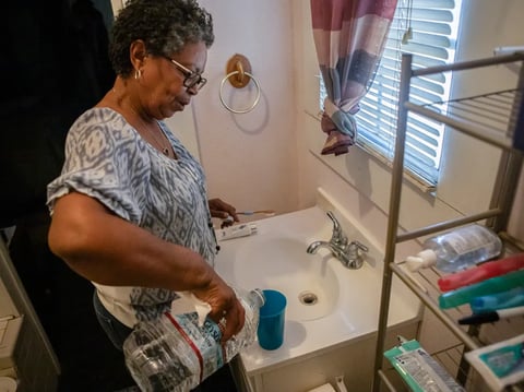 Sherry Hunter pours a cup of bottled water she uses to brush her teeth in her home in Allensworth on Sept.4, 2024.