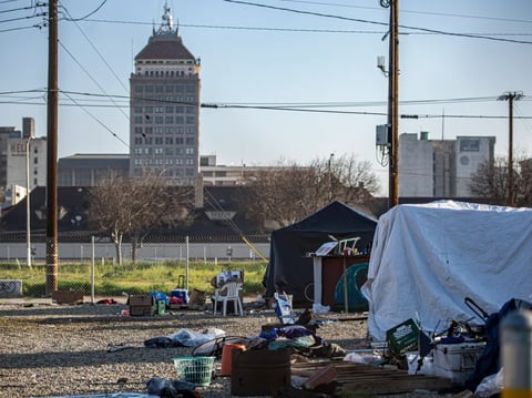 Tents in a homeless encampment line up against a fence in the Chinatown neighborhood just outside of downtown Fresno on Feb. 11, 2022.