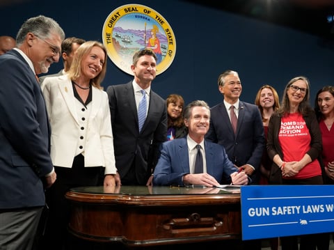 California Governor Gavin Newsom, seated, poses for a photo with lawmakers and gun control advocates at news conference where he signed three bills to strengthen California's gun control laws during a 2023 news conference in Sacramento, Calif.