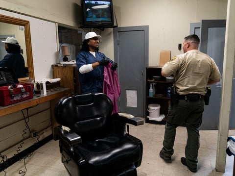 Gerald Massey talks with officer Chris Solorzano after giving him a haircut at Folsom State Prison, Thursday, May 4, 2023. He took up prison barbering to make money.