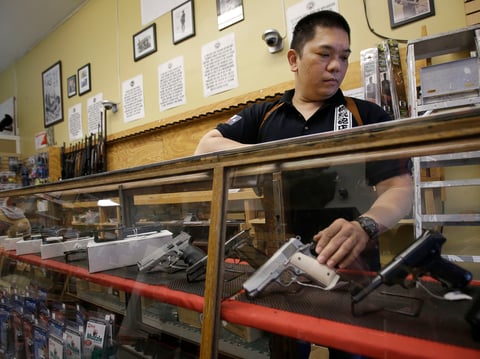 In this Sept. 30, 2015 file photo, High Bridge Arms general manager Steve Alcairo reaches into a display case of handguns while being interviewed in San Francisco.