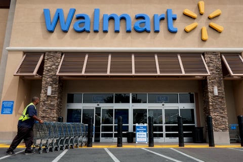 In this May 9, 2013, file photo, a worker pushes shopping carts in front of a Wal-Mart store in La Habra, Calif.