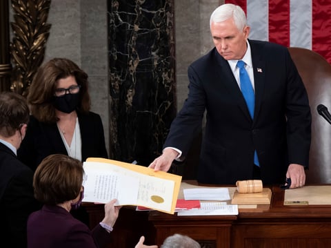 Vice President Mike Pence hands an electoral certificate to Sen. Amy Klobuchar, D-Minn., as he presides over a joint session of Congress as it convenes to count the Electoral College votes cast in the 2020 presidential election.