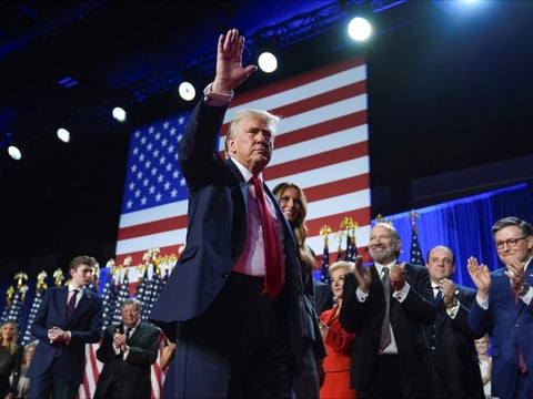 Former President Donald Trump waves as he walks with Melania Trump at an election night watch party at the Palm Beach Convention Center in West Palm Beach, Fla.