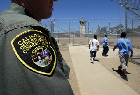 Inmates pass a Correctional Officer as they leave an exercise yard at the California Medical Facility in Vacaville, Calif. On Friday, Sept. 30, 2022.