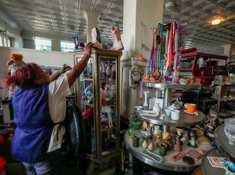 Employee Marylin Moreno grabs a pair of booths for a client at community thrift store in Los Angeles on Oct. 11, 2024.
