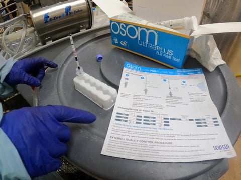 In this image provided by the USDA, a researcher performs a rapid antigen test on milk from a dairy cow inoculated against bird flu in a containment building at the National Animal Disease Center research facility in Ames, Iowa, on July 29, 2024.