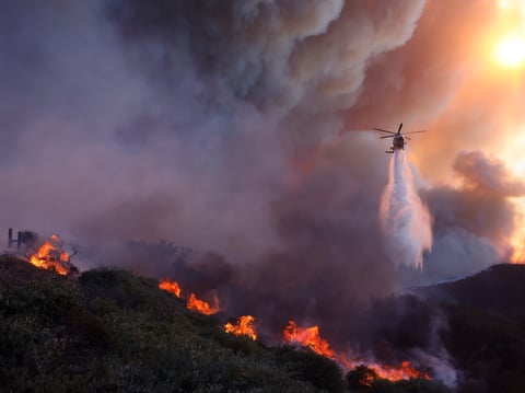 Water is dropped by helicopter on the advancing Palisades Fire in the Pacific Palisades neighborhood of Los Angeles, Tuesday, Jan. 7, 2025.