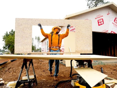 Jose Villanueva carries siding while building a home, Wednesday, Oct. 25, 2023, in Paradise, Calif. Most of the town burned in late 2018.