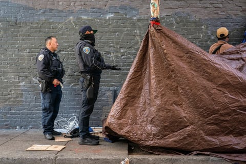 San Francisco police officers instruct an unhoused person to move personal items that are blocking the sidewalk on Cedar Street in San Francisco on Nov. 15, 2024.