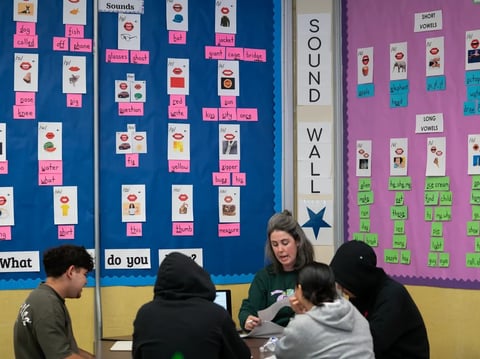 Teacher Katy Reese, center, works with students in a literacy class at Oakland International High School in Oakland on March 7, 2025.