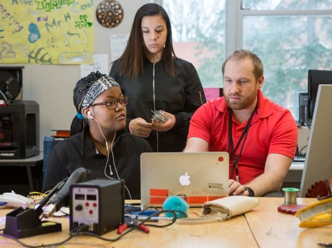 A teacher reviews students’ project notes on a computer.