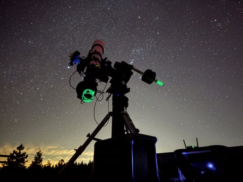 A photo of a telescope in front of the night sky.