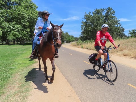 American River Bike Patrol spokesman Vic Massenkoff and Jeanlaurie Ainsworth with the American River Equestrian Patrol demonstrate how bicyclists should pass horses Thursday, May 29, 2025, along the American River Bike Trail in Carmichael.