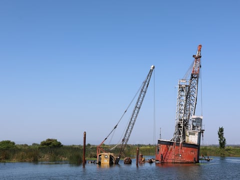 The 60-80 foot work barge Peanut (left) sits next to the 120-foot crane barge BD-245 (right) in the Sevenmile Slough area of the Sacramento-San Joaquin Delta, near Rio Vista and Isleton.