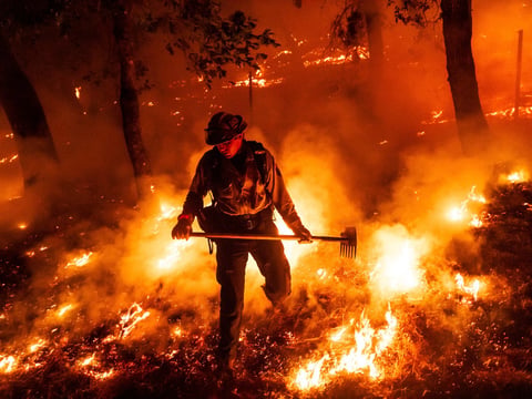 A firefighter battles the Pickett Fire burning in the Aetna Springs area of Napa County, Calif., on Saturday, Aug. 23, 2025