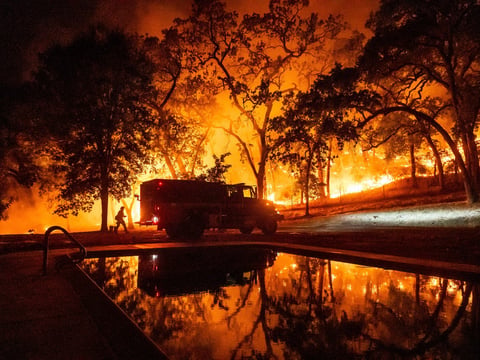 A firefighter battles the Pickett Fire burning in the Aetna Springs area of Napa County, Calif., on Saturday, Aug. 23, 2025.