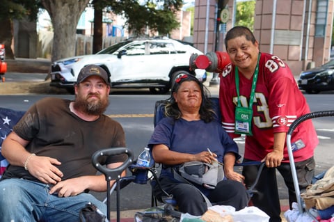 Josh Ames, left, sits with Jessica Davila, center, and her husband Felipe Davila outside Sacramento City Hall on Tuesday, July 29, 2025. The council voted later that day to approve a ban on overnight camping at the site.