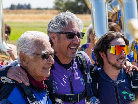 100-year-old Jimmy Hernandez (left) celebrating a successful jump at SkyDance Skydiving with his son, Andrew (middle), and grandson, Santiago (right).