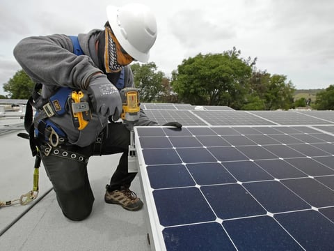 A worker installs solar panels in Hayward on April 29, 2020.