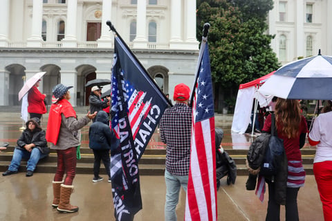 A supporter holds two flags as gospel music played at a memorial for Charlie Kirk outside the California Capitol on Tuesday, Oct. 14, 2025.