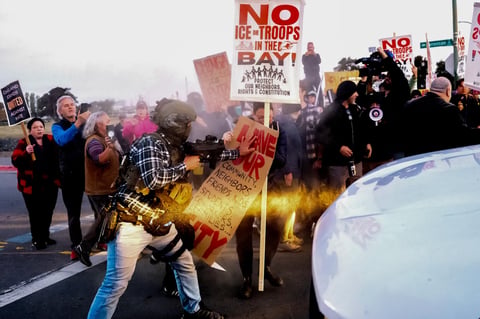 A person pushes a protester blocking a caravan of U.S. Customs and Border Protection personnel trying to enter Coast Guard Base in Alameda on Oct. 23, 2025.