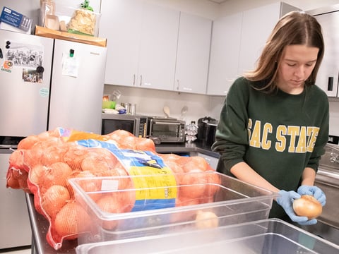 Brayden Lott, 20, unpacks onions Monday, Oct. 27, 2025, at Sacramento State’s campus food pantry. The food pantry assistant says onions are one of the most popular items students grab.