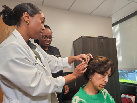 Dr. Ariel Cassar (left) and Audiology Doctoral Candidate Keaira Cooper (second from left) fit a smart cochlear implant for Arlene Concepcion (right) at the Maryjane Rees Center - Audiology Clinic Oct. 30, 2025. (Sarit Laschinsky/CapRadio)