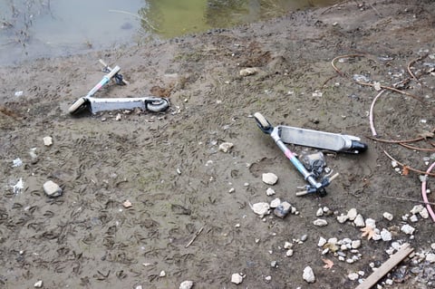 Two Bird rental e-scooters lay stuck in the mud along the riverbank near the Tower Bridge, just feet from the water on Wednesday, Jan. 21, 2026.