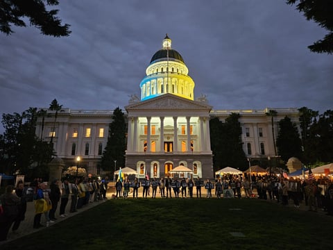 The California State Capitol lights up with the colors of the Ukrainian flag Feb. 24, 2026. Attendees carries photographs of Ukrainian civilians and soldiers killed in the fighting.