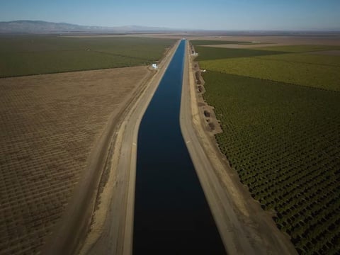 The San Luis Canal flows alongside farmland in Huron, Calif. Some farmers in the region are leaving land fallow because water is increasingly scarce.