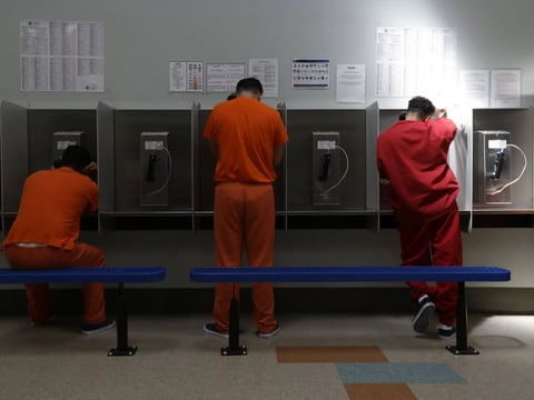 In this Aug. 28, 2019, file photo, detainees talk on telephones at the Adelanto ICE Processing Center in Adelanto, Calif.