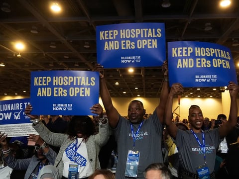 People supporting California's proposed billionaire tax hold signs at the 2026 California Democratic Party State Convention in San Francisco on Feb. 21, 2026.