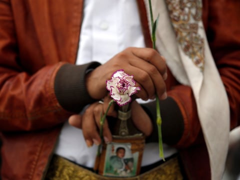 A member of the Baha'i faith holds a flower as he protests outside a state security court in Sanaa, Yemen, Sunday, April 3, 2016.