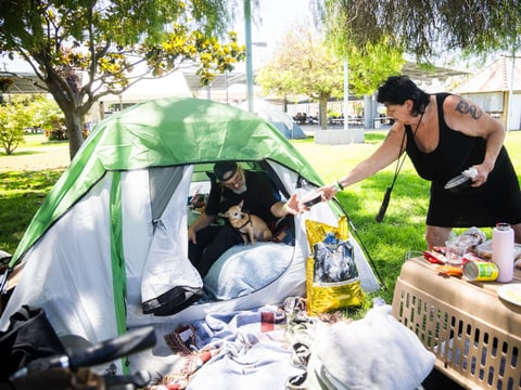 Jan De Jonge and fiancé Sher Stuckman set up a tent with their belongings and pet outside the Elks Lodge in Garden Grove, Calif., on Monday, May 25, 2026.