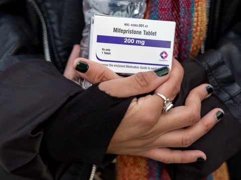 FILE - An abortion- rights activist holds a box of mifepristone pills as demonstrators from both anti-abortion and abortion-rights groups rally outside the Supreme Court in Washington, Tuesday, March 26, 2024.