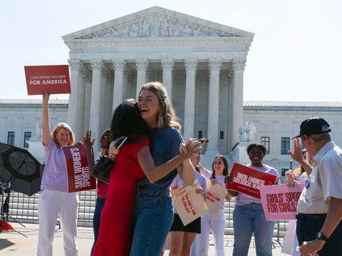 Activist Macy Charles, center right, hugging Penny Nance, as they celebrate the transgender athletes ruling outside of the Supreme Court on Capitol Hill, Tuesday, June 30, 2026, in Washington.
