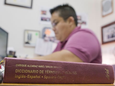 A well-used Spanish-English legal dictionary sits on the desk of court interpreter Adriana Hinojosa.