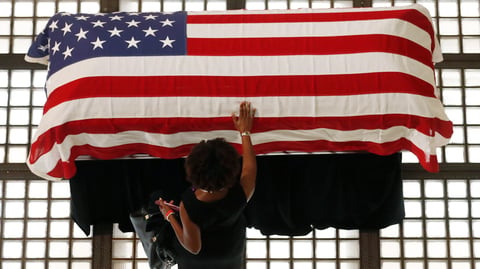 A mourner pauses by the casket of Rep. John Lewis lying in repose at the state capital on Wednesday in Atlanta. Lewis, who carried the struggle against racial discrimination from Southern battlegrounds of the 1960s to the halls of Congress, died on July 17.