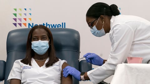 Sandra Lindsay (left) a nurse at Long Island Jewish Medical Center, is inoculated with the Pfizer-BioNTech COVID-19 vaccine by Dr. Michelle Chester on Monday in New York.
