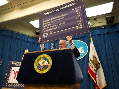 Calif. Gov. Jerry Brown holds up a chart of the state's long-term debts as he presents his budget proposal in January 2014.