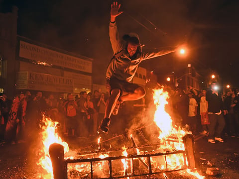 A man jumps over some debris that has been set on fire in the Mission district after the San Francisco Giants beat the Kansas City Royals to win the World Series on Wednesday, Oct. 29, 2014, in San Francisco.