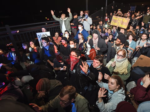Protesters and police officers face off on a pedestrian bridge over Interstate 80 shortly in Berkeley, Calif.
