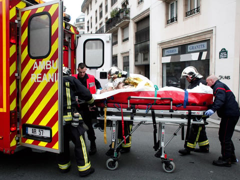 An injured person is transported after a shooting Wednesday at the Paris office of the French satirical weekly Charlie Hebdo. At least 12 people were killed during the attack, according to police.
