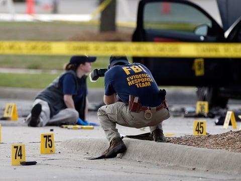 FBI crime scene investigators document the area around two deceased gunmen and their vehicle outside the Curtis Culwell Center in Garland, Texas, Monday, May 4, 2015.