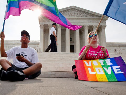 Carlos McKnight, 17, of Washington, left, and Katherine Nicole Struck, 25, of Frederick, Md., hold flags in support of gay marriage as security walks behind outside of the Supreme Court in Washington, Friday June 26, 2015. 