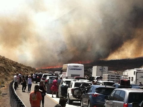 Bystanders look on along Interstate 15 on the Cajon Pass, Friday, July 17, 2015, near San Bernadino, as a fast-moving wildfire swept across the freeway. At least 20 vehicles and five homes burned in the fire.
