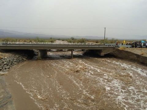 Waters rush under an the elevated portion westbound Interstate 10 as emergency crews respond to the collapse of the eastbound section, Sunday, July 19, 2015, in Desert Center, Calif.