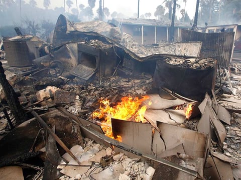 Flames burn in the gutted remains of a mobile home destroyed at Korth's Pirate's Lair Marina in Isleton, Calif., Thursday, July 30, 2015. Fire crews from multiple agencies battled the fire that destroyed multiple homes and damaged several others.